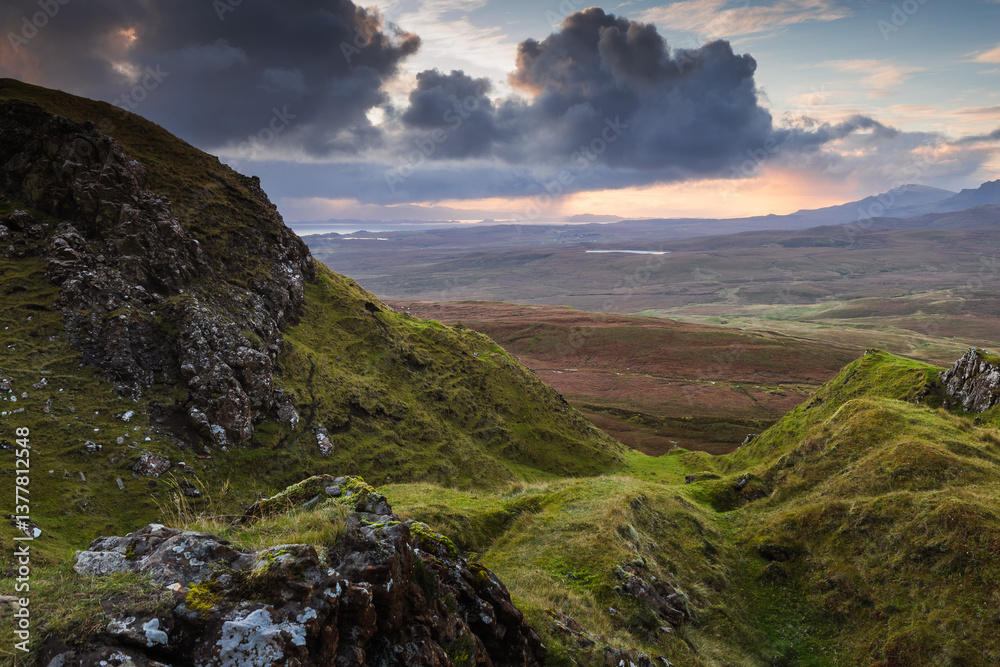 Autumn light bathes the Quiraing on Skye, casting long shadows over its dramatic cliffs and rolling hills. The landscape glows with golden hues, a breathtaking Highland scene.