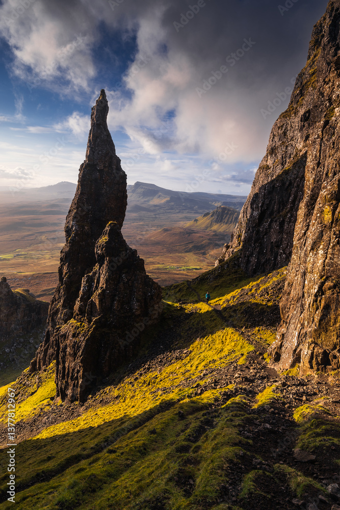 Autumn light bathes the Quiraing on Skye, casting long shadows over its dramatic cliffs and rolling hills. The landscape glows with golden hues, a breathtaking Highland scene.