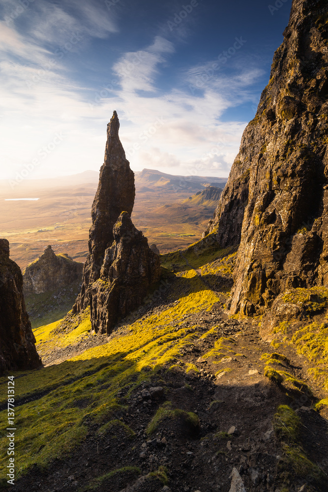 Autumn light bathes the Quiraing on Skye, casting long shadows over its dramatic cliffs and rolling hills. The landscape glows with golden hues, a breathtaking Highland scene.