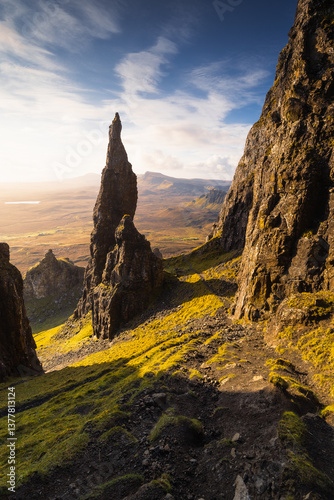 Obraz na płótnie Autumn light bathes the Quiraing on Skye, casting long shadows over its dramatic cliffs and rolling hills. The landscape glows with golden hues, a breathtaking Highland scene. w salonie