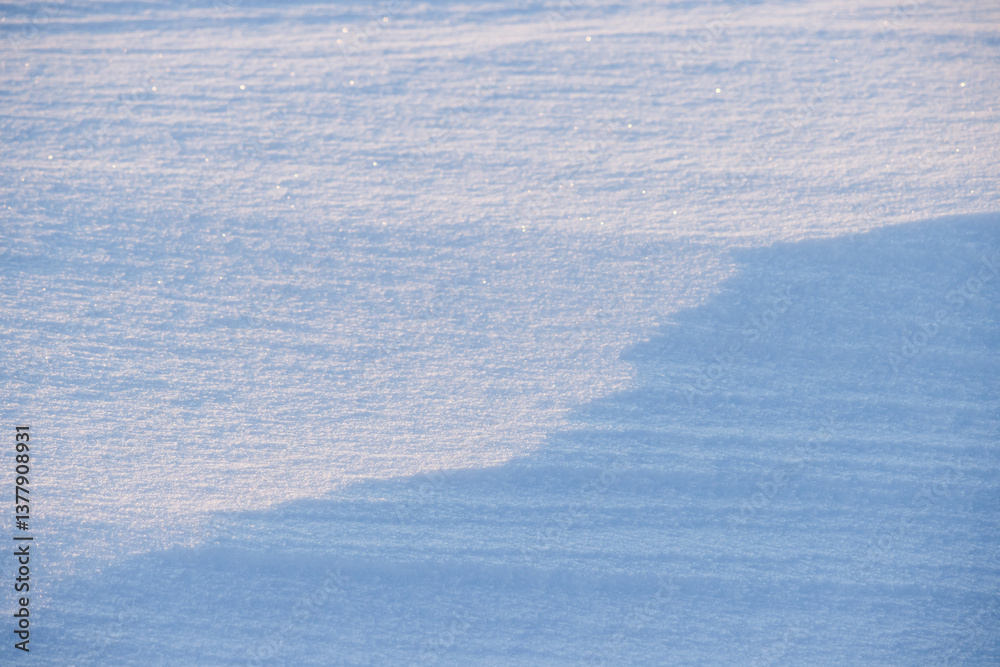 Beautiful winter background with snowy ground. Natural snow texture. Wind sculpted patterns on snow surface. Closeup top view with copy space.