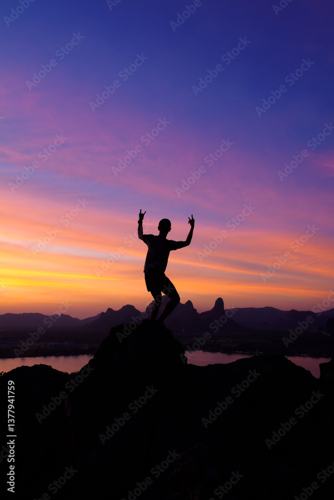 Silhouette of man standing on the hill at Phu Sub Lek in Lopburi, Thailand. Silhouette of positive man celebrating on mountain top with arms raised up. Silhouette of man standing on the hill at Phu Sub Lek in Lopburi, Thailand. Silhouette of positive man celebrating on mountain top with arms raised up.