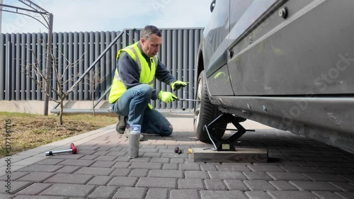 A guy changes tire on street to summer tire in nature