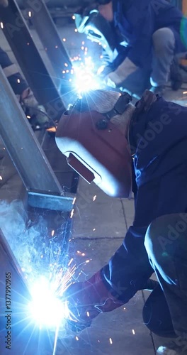 Workers welding and grinding metal construction in metal industry - slow motion. Close up shot, lots of sparks in the factory