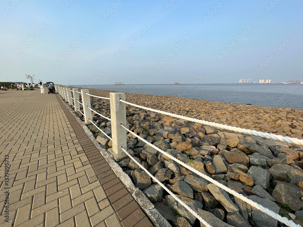 Fototapeta premium Beach with rock fragments and blue sky background with rope barrier