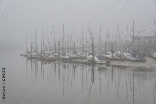 Boats moore in marina on River Arun at Littlehampton in West Sussex, England, calm and misty.