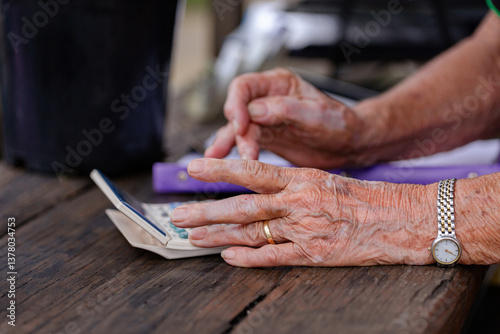 Senor woman’s hands adding up purchase amount at counter of nursery garden small business  photo