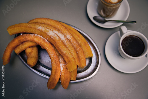 Churros popular delicious spanish food with hot chocolate, sugar and coffe on restaurant table. Flat lay