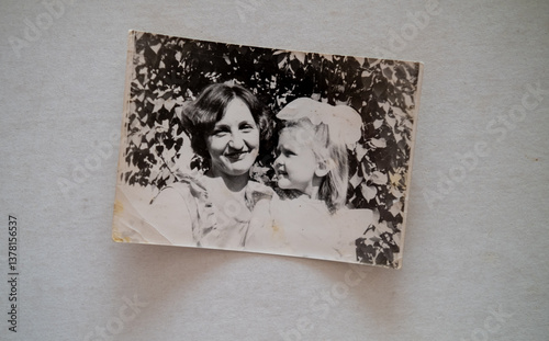 Female hand is holding black and white old photo of her grandmother with her daughter. Vintage photo album with photos. Family and life values concept.
