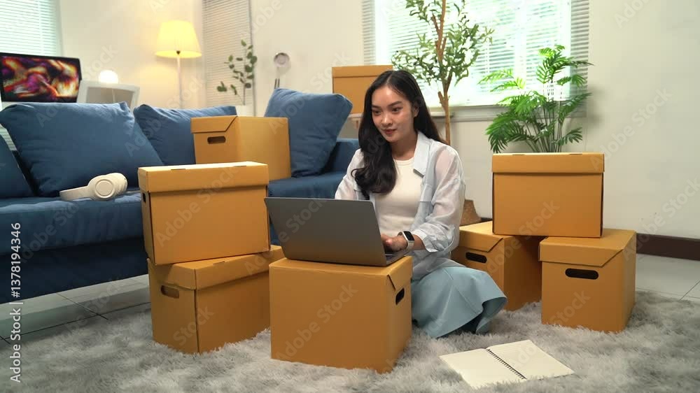 Professional online seller processing e-commerce orders, preparing packages for shipping while working from home living room, surrounded by cardboard boxes and managing business using laptop Professional online seller processing e-commerce orders, preparing packages for shipping while working from home living room, surrounded by cardboard boxes and managing business using laptop