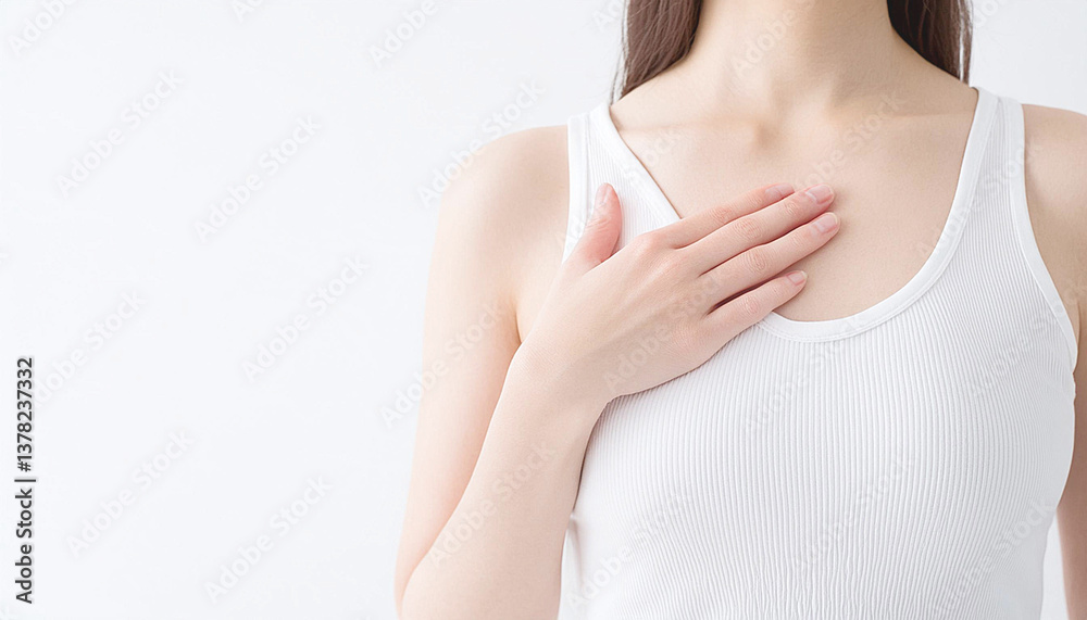 白いタンクトップを着た日本人女性。胸に手を当てている。乳がん検診 白いタンクトップを着た日本人女性。胸に手を当てている。乳がん検診