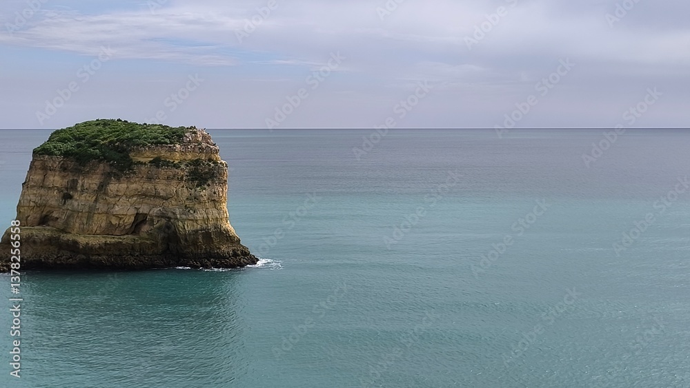 Naklejka premium Aerial footage of a hidden paradise featuring a rock formation island. Captured 04/04/2025 in Portimao, Portugal