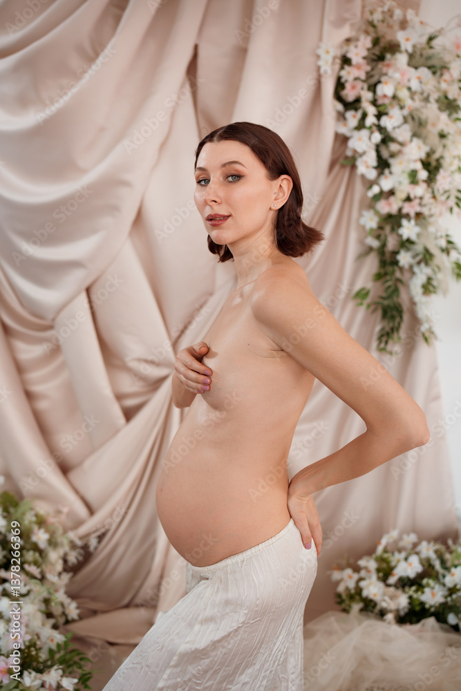 Pregnant young woman posing gracefully in a floral decorated setting