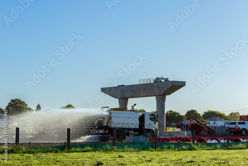 Water spraying truck dampening down ground to minimize dust on construction site