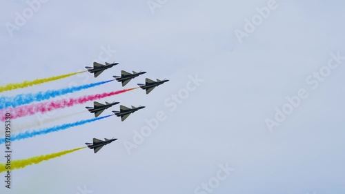 Team of fighter jets performs a breathtaking aerobatic maneuver with precision formation flying, leaving color smoke trails against a clear sky during an air show in Thailand photo