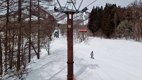 POV from ski chairlift with skiers and sun. Tsugaike, Hakuba Valley