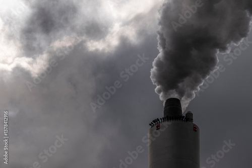 Close-up of factory smokestack with dark emissions. Pollution and climate change concept in minimal industrial scene with moody atmosphere.