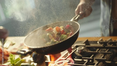 Slow-motion cinematic shot of a chef hand tossing multicolored vegetables in wok pan in restaurant kitchen