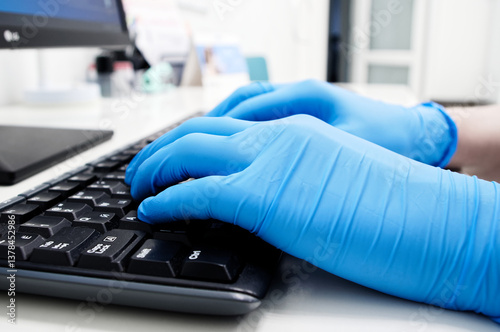 A doctor or recearcher wearing gloves typing on a keyboard