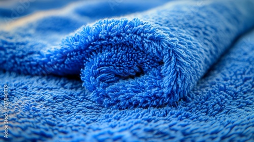 Close-up of rolled blue microfiber towel. Soft, textured fabric