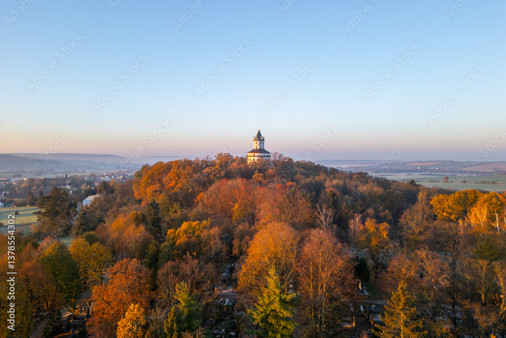 Fototapeta premium The Baroque Humprecht chateau glows softly in the autumn sunrise, surrounded by vibrant foliage above Sobotka in the picturesque Bohemian Paradise of Czechia.