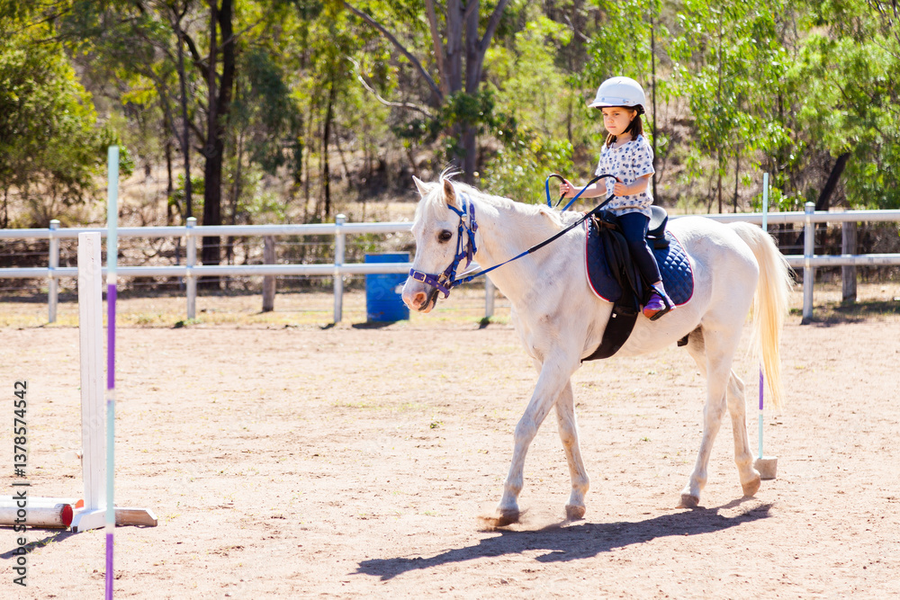 Five year old horse rider doing pole bending on white pony Five year old horse rider doing pole bending on white pony