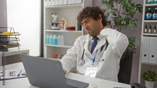 Wallpaper Mural Handsome hispanic man in clinic wearing lab coat feeling neck pain while working on computer in medical office with stethoscope and office supplies surrounding. Torontodigital.ca