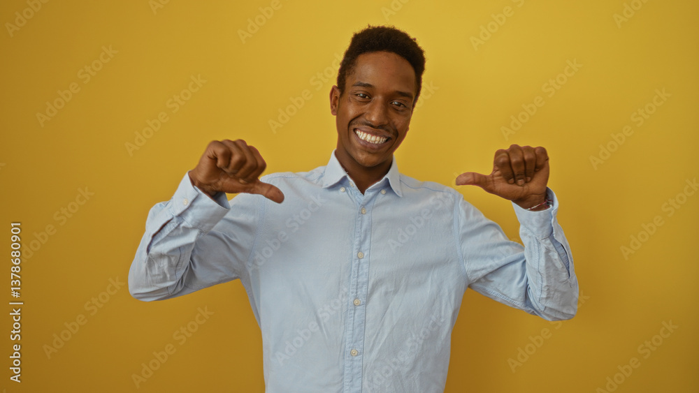 Young black man smiling confidently, pointing thumbs at himself against a vibrant yellow background wearing a blue shirt, embodying positivity and self-assurance.