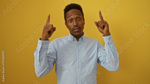 Young man pointing upwards over isolated yellow background with a confident expression highlighting modern fashion and emotion