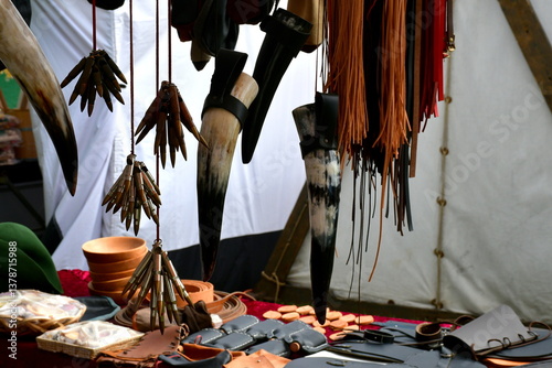 A view of a small shop set up during a medieval fair in Poland offering various historic items, including straps, horns, jewelry, items of clothing, sunglasses, and many others