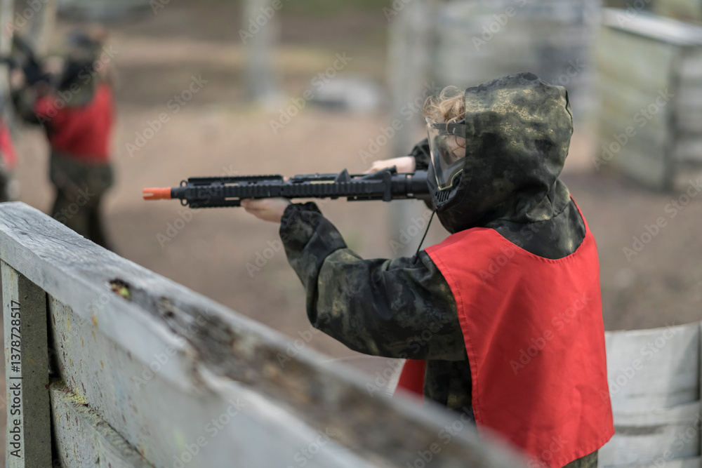 Fototapeta premium Kids playing airsoft. Team gun play on an outdoor sports field