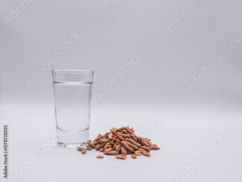 A glass of vodka and sunflower seeds on a light background, front view