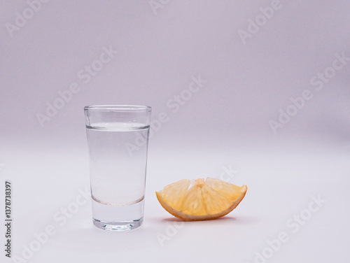A glass of vodka and a slice of lemon, on a white background, front view