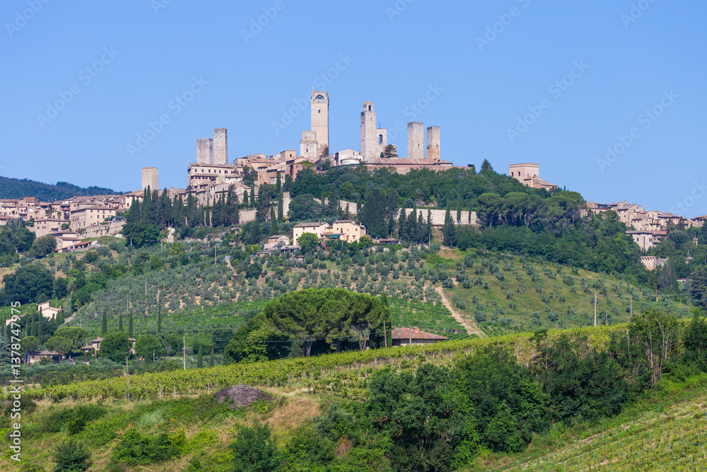 San Gimignano village, Italy: green countryside, blue sky, hill panorama with town and towers