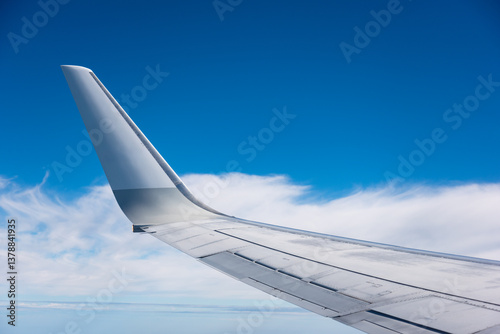 Fototapeta Naklejka Na Ścianę i Meble -  airplane wing against clouds and blue sky