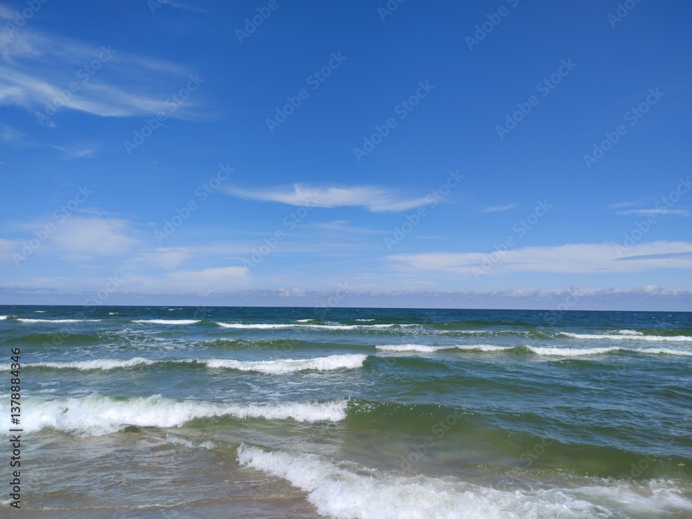 Wide Angle View of Baltic Seascape with Rolling Waves Meeting Sandy Shore Under Bright Blue Sky Wide Angle View of Baltic Seascape with Rolling Waves Meeting Sandy Shore Under Bright Blue Sky