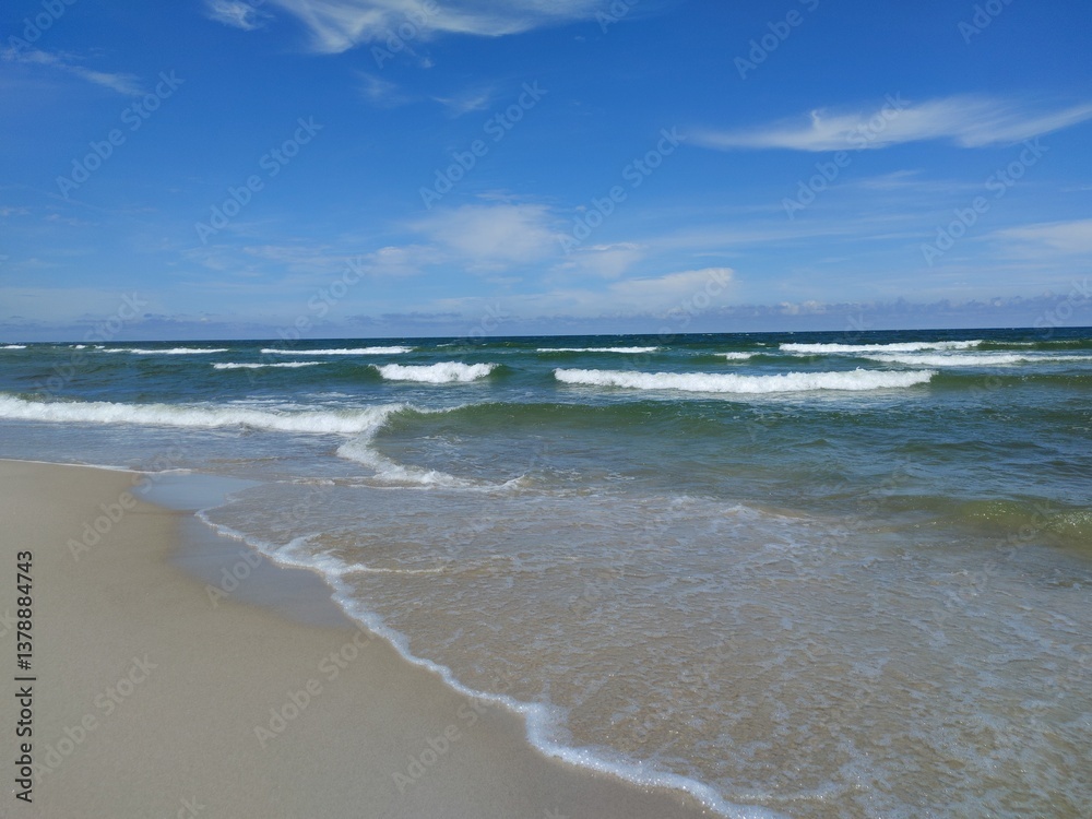 Pristine Deserted Beach with Gentle Foam-Edged Waves Meeting Sandy Shore Under Clear Blue Summer Sky Pristine Deserted Beach with Gentle Foam-Edged Waves Meeting Sandy Shore Under Clear Blue Summer Sky