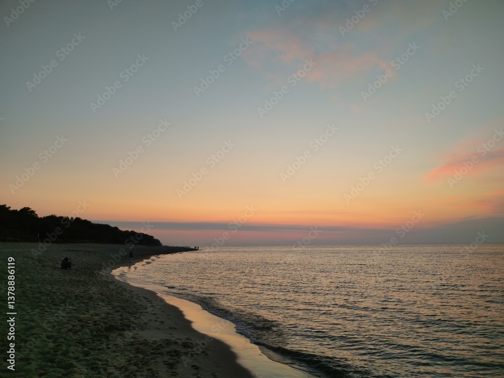 Obraz premium Serene Evening at Baltic Shoreline with Pink Sunset Sky Illuminating Coastal Curve and Creating Peaceful Atmosphere at Dusk