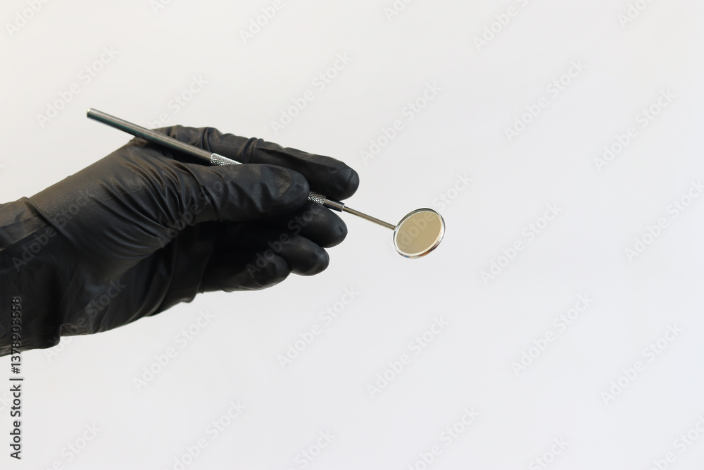 Dental instrument in the hands of a dentist, close-up. Dental mirror. Diagnostic dental instrument. Hand in black medical gloves with a dental mirror on a light background