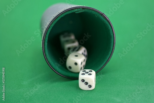 Rolling dice in a cup on a green felt surface during a game nigh