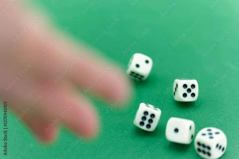 Playing dice on a green table with a hand reaching for the rolli