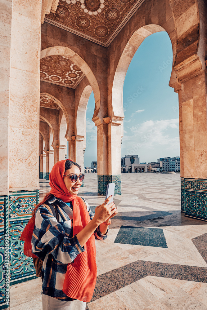 Young woman tourist taking selfie with smartphone in front of Hassan II Mosque in Casablanca, Morocco