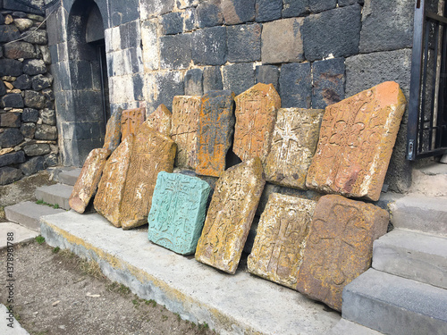 Display of sacred stone tablets leaning along ancient religious wall Assorted engraved slabs rest solemnly against aged stone backdrop in quiet reverence