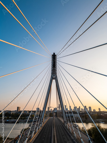 modern metal cable bridge over Vistula river at sunset, contemporary geometric architecture, cable-stayed bridge at city skyline, symmetry and architectural urban contrast, Warsaw