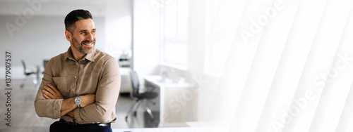 Successful middle aged businessman in shirt posing with crossed hands, looking away and smiling, working in light office interior, free copy space, panorama
