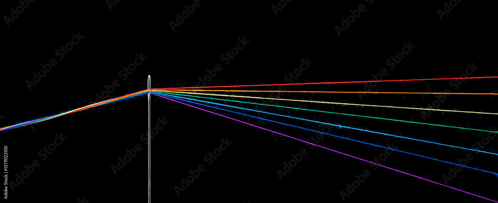 Obraz premium multi-colored threads for sewing in the form of a rainbow pass through an antique needle on a black background