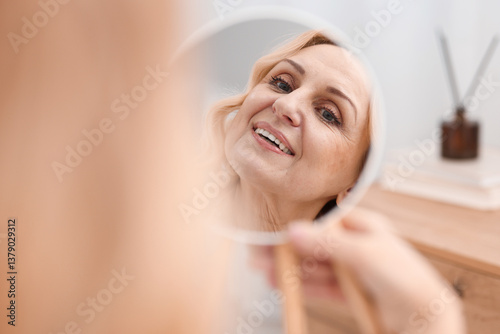 Smiling middle aged woman with round mirror at home