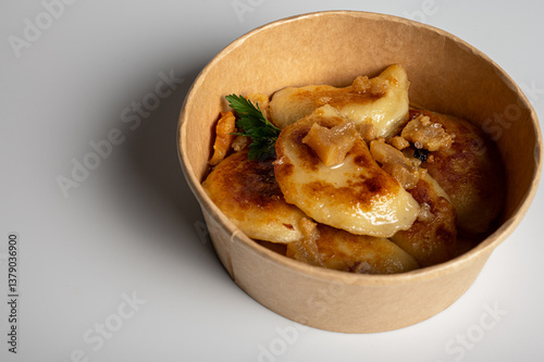 Obraz na płótnie Fried dumplings with golden crust and crispy pork cracklings in a kraft paper bowl. Traditional Eastern European food, close-up, delicious street food concept w salonie
