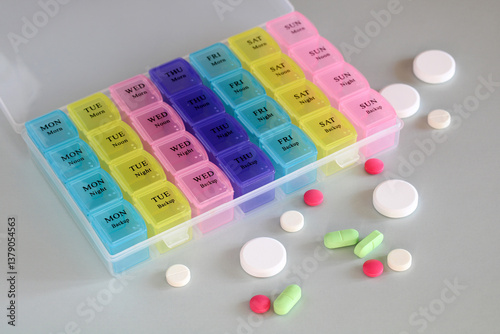 Weekly pill organizer box with colorful pills for daily medication. pillbox