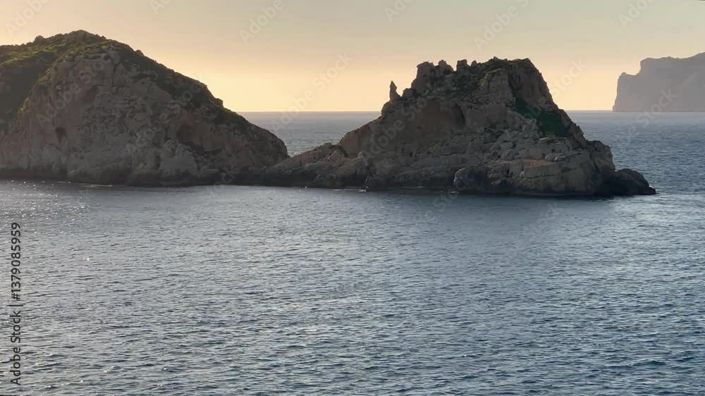 Gusts of wind cause local ripples on the calm surface of the sea. The frame shows wild cliffs near the shore. The island of Mallorca. Spain. Gusts of wind cause local ripples on the calm surface of the sea. The frame shows wild cliffs near the shore. The island of Mallorca. Spain.